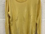 a yellow sweater hanging on a hanger against a white brick wall