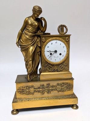 a statue of a woman holding a clock on a table