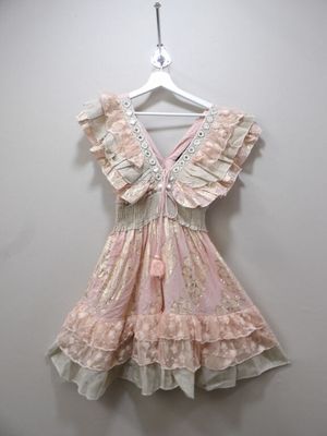 pink and white dress hanging on a hanger against a white wall