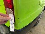 a person that is holding a sticker on the back of a green van