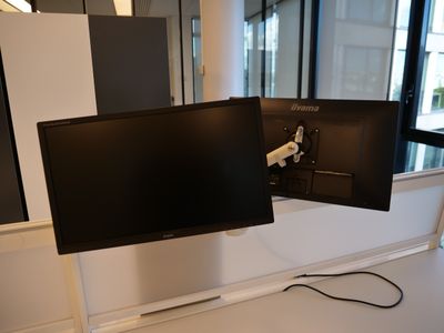 deux écrans posés sur un bureau devant une fenêtre
