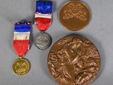 three medals and a bronze medal on a gray surface