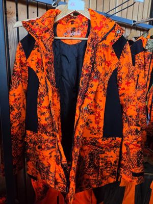 an orange and black jacket hanging on a rack in a room