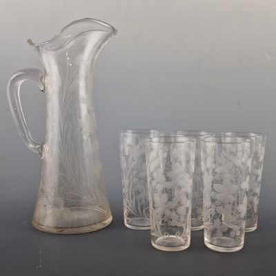 four glasses and a pitcher sitting next to each other on a table