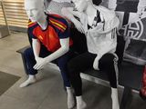 two mannequins sitting on a bench in front of a wall