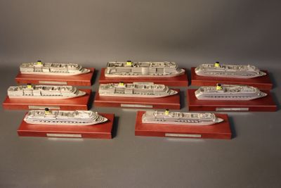 six model ships are lined up on wooden bases
