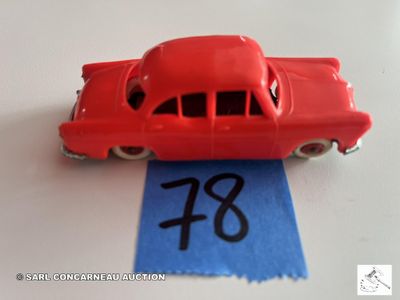 une petite voiture rouge posée sur un ruban bleu