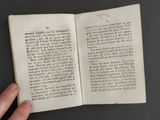 someone is holding a book open on a table with a black background