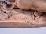 statue of a woman laying on a rock with a bird in her hand