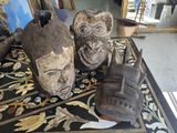trois masques en bois posés sur une table dans une pièce