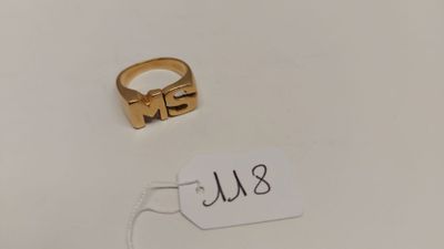 une bague en or à laquelle est attachée une plaque portant un nom