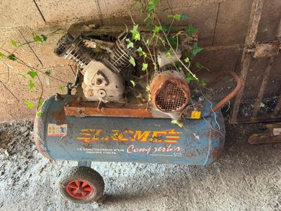 a small air compressor sitting on the ground next to a wall