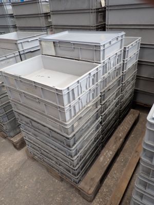 de nombreux conteneurs en plastique empilés sur une palette dans un entrepôt