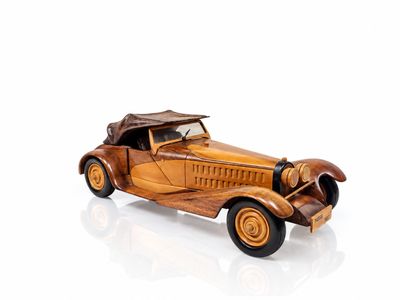 a wooden model of an old car on a white surface
