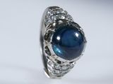 a close up of a ring with a blue stone surrounded by diamonds