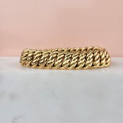 a close up of a gold bracelet on a marble surface