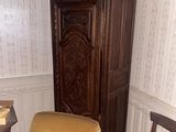 two chairs in a corner of a room with a grandfather clock on the wall