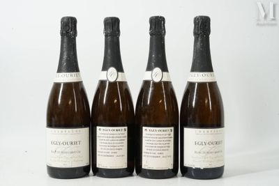 quatre bouteilles de vin sont alignées sur une surface blanche