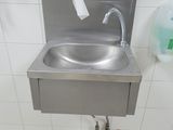 a stainless steel sink in a public restroom with a paper towel dispenser