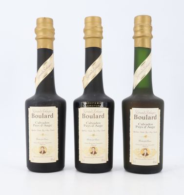 trois bouteilles de vin sont alignées sur une surface blanche