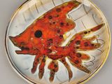 une assiette en verre sur laquelle est posé un poisson, posée sur une table