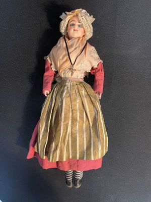 an old fashioned doll is sitting on a black surface