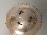 a silver shell with a face on it on a table