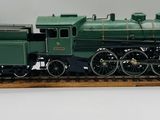 une maquette de train vert posée sur un socle en bois