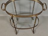 a brass and glass serving cart with two trays on wheels