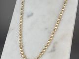 un collier de perles d'or posé sur un socle en marbre