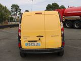 a yellow van parked in a parking lot with a red truck in the background