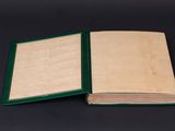 an open book on a black surface with a green cover