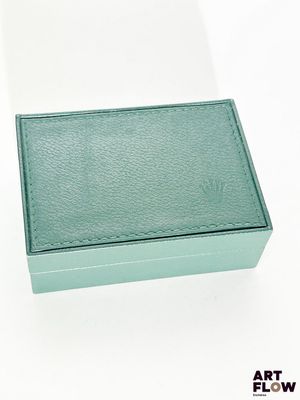 une boîte verte posée sur une surface blanche