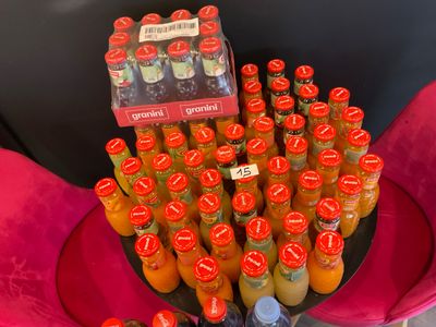 many bottles of orange juice sitting on a pink chair