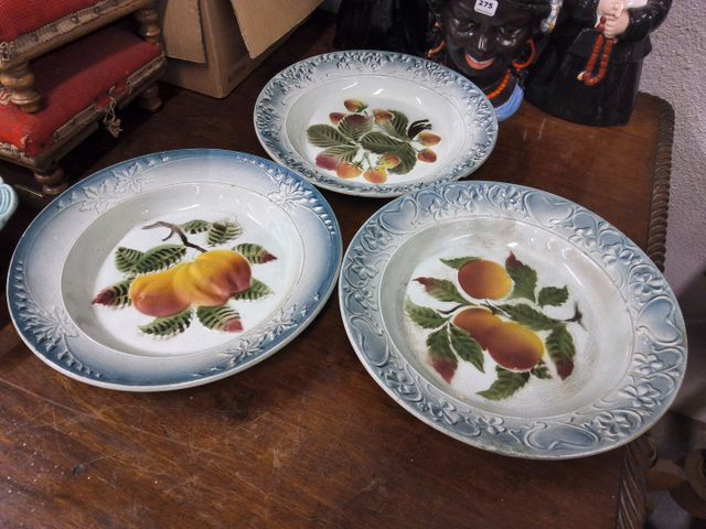 Suite de trois assiettes en faïence décor de fruits. Accidents