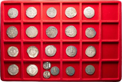 an assortment of silver coins in a red tray on a white surface