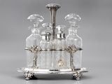 an antique silver plated liquor set with four bottles on a stand