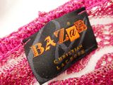 the label of a pink sweater with a black and orange design on it