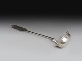 cuillère en argent avec un manche, posée sur une surface blanche