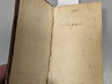 Quelqu'un tient dans sa main un vieux livre sur lequel figurent des inscriptions.