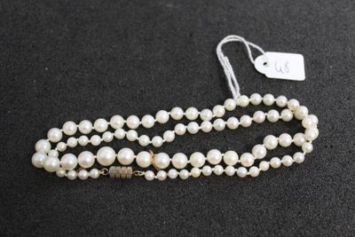 a close up of a necklace with pearls on a black surface
