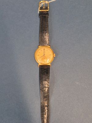 une image représentant une montre-bracelet posée sur une surface bleue, avec une chaîne