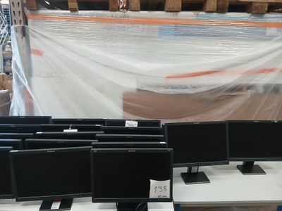de nombreux écrans d'ordinateur posés sur une table dans un entrepôt