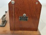 a small wooden clock on a table with a metal handle