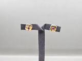 une paire de boucles d'oreilles en or et rubis posée sur un socle noir