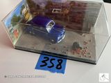 une petite voiture bleue dans une boîte transparente posée sur une table