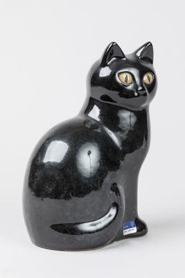une figurine de chat noir posée sur une surface blanche