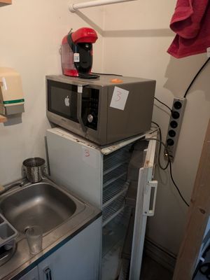 une petite cuisine équipée d'un évier et d'un micro-ondes