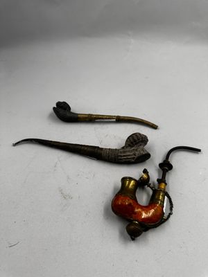 une pipe et un porte-pipe posés sur une surface blanche