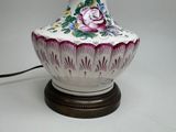a white vase with a pink rose on it on a table